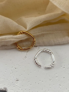 Close-up of gold and silver twisted cable knot rings on natural textured stone