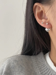 Gros plan de boucles d'oreilles en forme de cœur en métal liquide et clous en argent