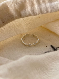 Detail of 925 sterling silver open ring with oval link design on beige linen bag