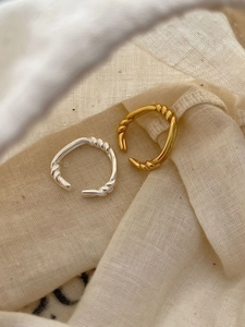 Detailed close-up of textured gold and silver twisted knot rings on a beige linen fabric