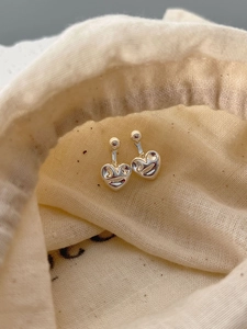 Vue macro de boucles d'oreilles cœur en argent 925 sur pochette en lin