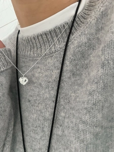 Détail macro du pendentif cœur en argent S925 avec lettre B sur un pull gris