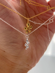 Primer plano de collares de flores de plata S925 dorados y plateados en mano