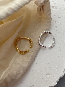 Detail of twisted woven texture open rings in gold and silver finish on stone