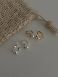Détails des créoles en argent 925 et or avec perles blanches sur un fond en tissu tressé