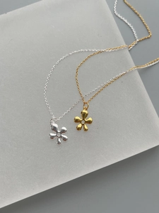Detalle de colgantes de flores de plata de ley S925 minimalistas en acabados oro y plata