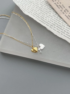 Macro detail of heart and key pendants on fine gold and silver chains over vintage paper