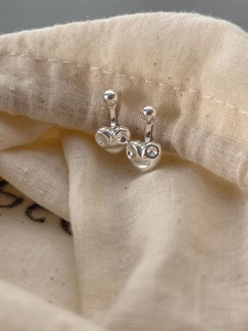 Vue macro de boucles d'oreilles cœur en argent poli sur un pochon à bijoux en lin