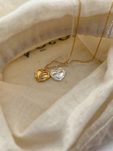 Vue rapprochée de pendentifs cœurs en or et argent avec lettre B et texture lave