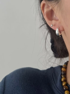 Gros plan détaillé des créoles croissant en argent S925 et des puces d'oreilles épurées