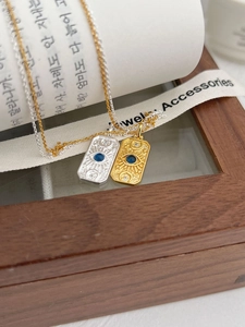 Detail of sunburst pendant necklace with blue gem in gold and silver finishes