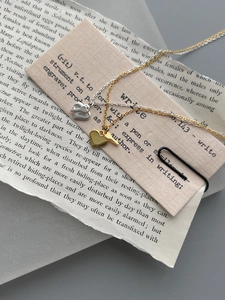 Macro detail of gold and silver heart key pendant necklaces on vintage paper