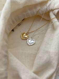 Vue macro de pendentifs cœur en argent 925 avec lettre B dorée et argentée