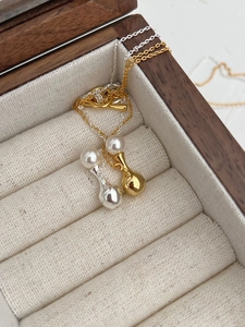 Detail of S925 silver pearl teardrop necklaces in gold and silver finish on display