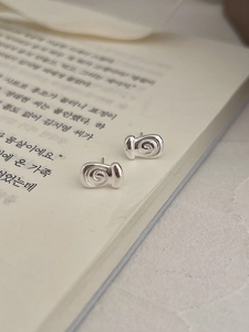 Makroaufnahme von silbernen spiralförmigen Ohrsteckern auf einem offenen Buch
