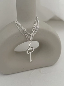 Detail of minimalist 925 sterling silver multi-layer key pendant necklace on a ceramic vase