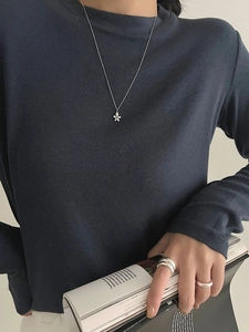 Detalle de collar de flores de plata y anillos minimalistas usados por una modelo