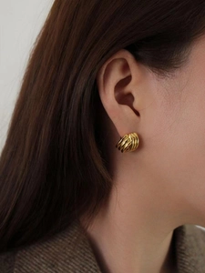 Gros plan de boucles d'oreilles dorées géométriques au design entrelacé moderne