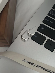 Détail de boucles d'oreilles créoles croissant en argent S925 sur un clavier d'ordinateur