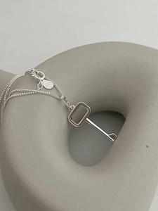 Macro detail of S925 sterling silver key necklace showing S925 stamp and minimalist pendant