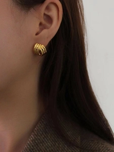 Gros plan d'un modèle portant une boucle d'oreille dorée multicouche à spirale torsadée