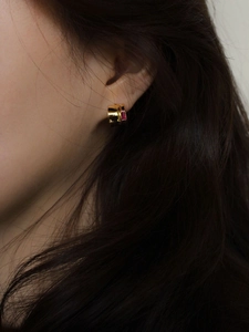 Close-up of 925 silver gold earring with rectangular pink gemstone on a female ear
