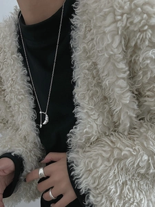 Sterling silver croissant necklace styled with black turtleneck and cream fleece jacket