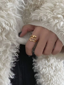 Close-up of a minimalist golden wrap ring with double-layer design on model's index finger