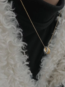 Macro view of three-ring necklace featuring brushed gold and crystal-set silver details