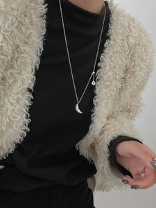 Silver croissant pendant necklace on model wearing black turtleneck and white fleece coat