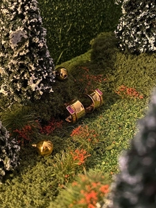 Miniature forest scene showing a golden C-shaped earring with a pink cubic zirconia gemstone