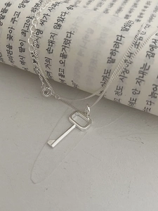 Minimalist 925 sterling silver necklace with key pendant on a stylized newspaper backdrop