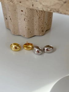 Close-up of minimalist bean-shaped stud earrings in gold and silver mirror finish