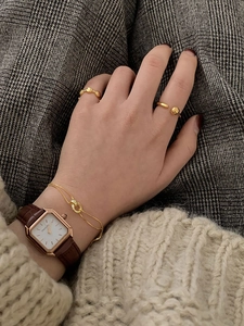 Minimalist gold beaded rings and vintage square watch with brown leather strap