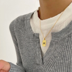 Gold sun god necklace with evil eye pendant on model for a minimalist fashion look