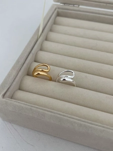 Close-up of minimalist gold and silver wavy open rings in a grey velvet jewelry box