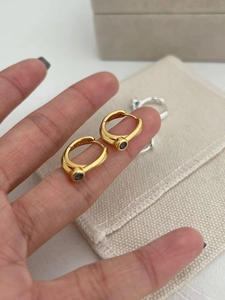 Close-up of S925 sterling silver stamp on gold earrings with blue zircon stones