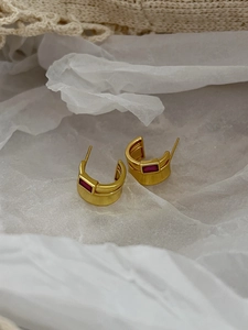 Macro shot of gold-plated 925 silver C-shape stud earrings with rectangle red zircon