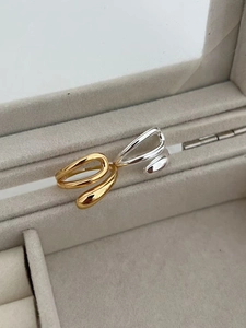 Detailed view of minimalist gold and silver teardrop rings on velvet jewelry stand
