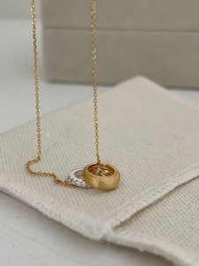 Macro detail of interlaced gold brushed and silver gemstone-encrusted ring pendants
