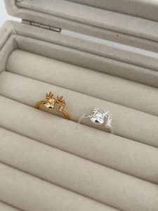 Detail shot of gold and silver reindeer rings with small charms in a velvet jewelry box