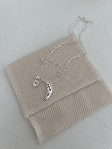 Detail of silver croissant pendant and round tag on minimalist S925 sterling silver chain