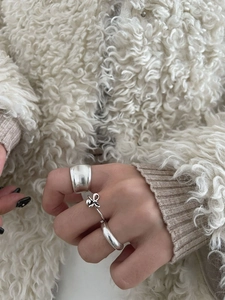 Ensemble de trois bagues nœud en argent S925 porté au doigt sur fond de tricot hivernal
