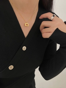 Close-up of a gold 925 silver necklace with a red sunburst pendant on a black sweater