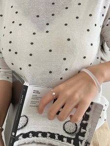 Minimalist silver bead open ring and translucent white bangle worn in a lifestyle setting