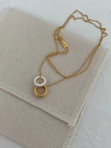 Detail of two-tone interlocking rings pendant with zircon stones on golden O-chain