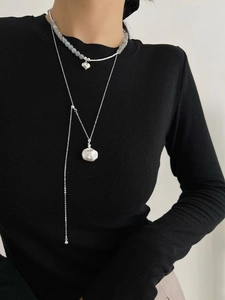 Gros plan de colliers superposés en argent avec pendentif cœur et disque martelé