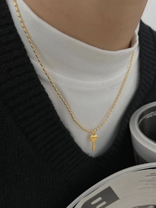 Détail d'un pendentif clé cœur en argent 925 gravé LOVE sur une fine chaîne perlée dorée