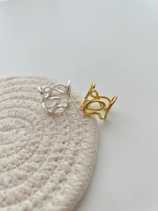 Close-up of irregular hollow silver and gold rings on a beige woven surface