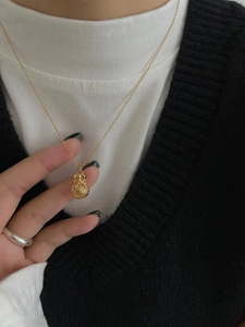 Dettaglio di una collana vintage dorata con ciondolo a sacchetto portafortuna e caratteri cinesi